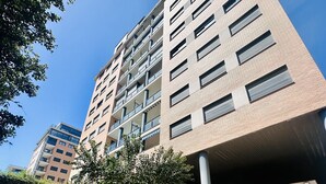 A multi-story building with a modern architectural design, featuring a flat roof and a series of windows.