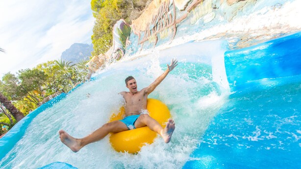 A person on a yellow raft in a water slide.