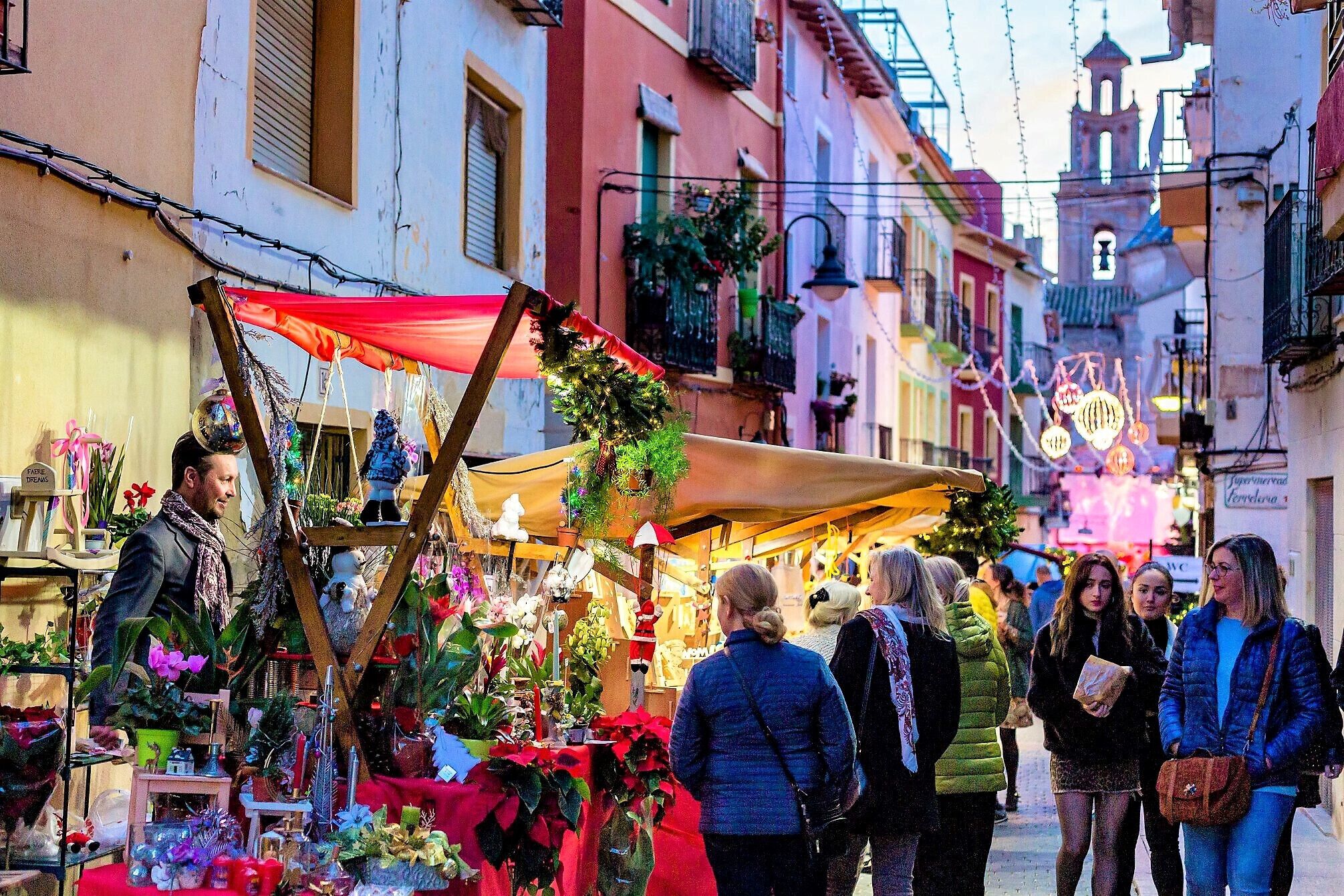 A narrow street with a market stall selling plants and flowers.