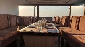 A dining area with a long table set for a meal, surrounded by upholstered chairs.