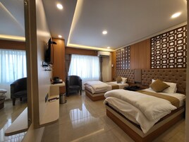 A hotel room with two beds, a desk, a chair, and a decorative wall panel.