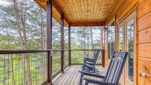 Eine Holzterrasse mit überdachter Veranda, Holzgeländern und zwei Stühlen.