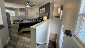 Un dormitorio con una cama, un ventilador de techo y una ventana con persianas.