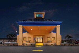 A hotel entrance with a blue roof and a sign indicating it is a Quality Suburban hotel.