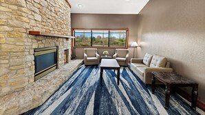Un salon doté d’une cheminée en pierre, d’une grande fenêtre et d’un tapis à rayures bleues.