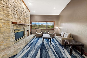 A living room with a stone fireplace, a large window, and a blue striped carpet.