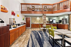 A hotel kitchen with a dining area, a kitchenette, and a wooden staircase.
