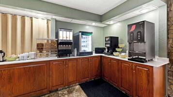 A kitchen with wooden cabinets, a coffee machine, a refrigerator, and a microwave.