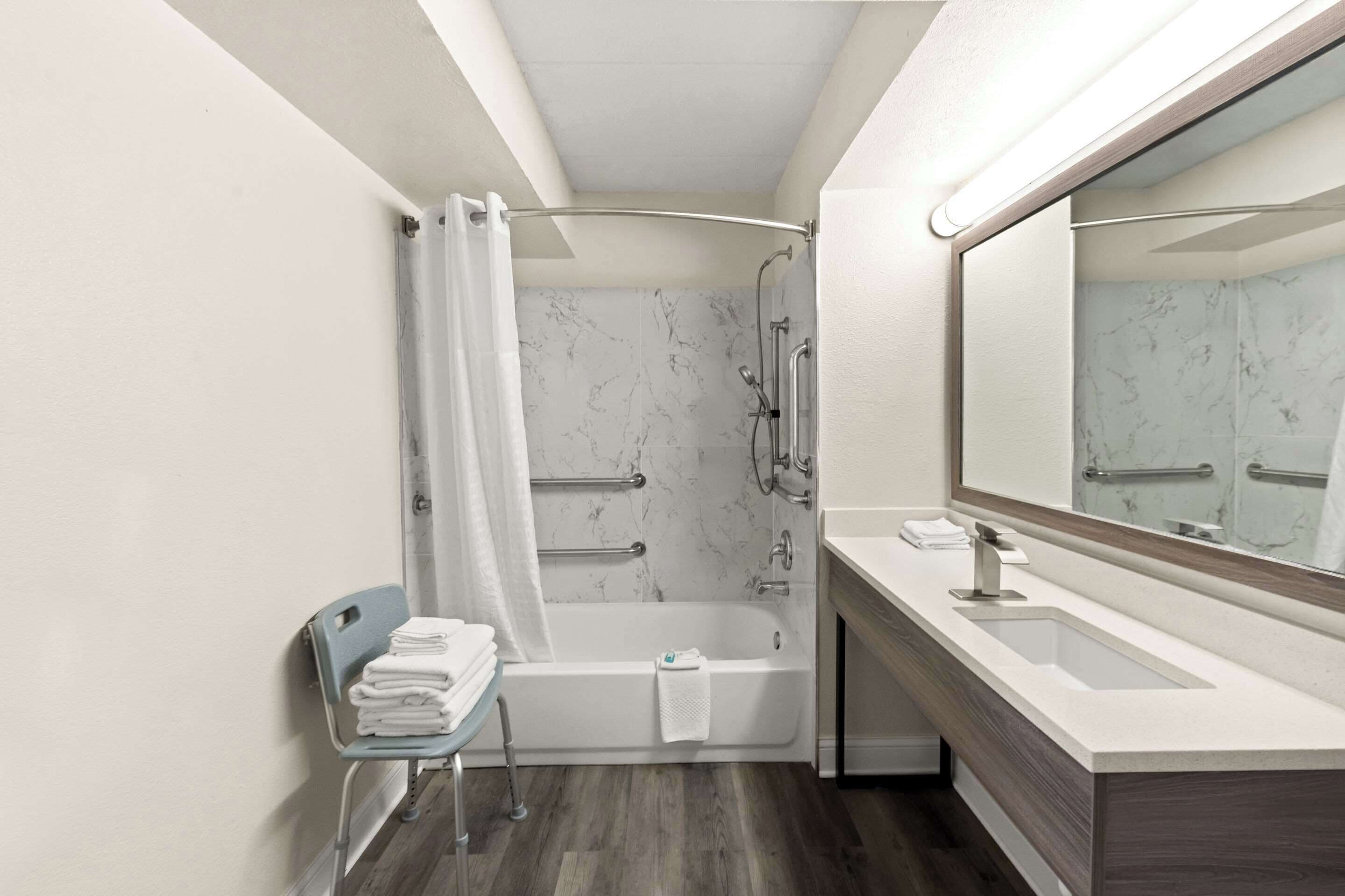 A modern bathroom with a bathtub, a vanity with a sink, and a mirror.
