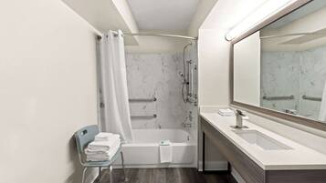 A modern bathroom with a bathtub, a vanity with a sink, and a mirror.