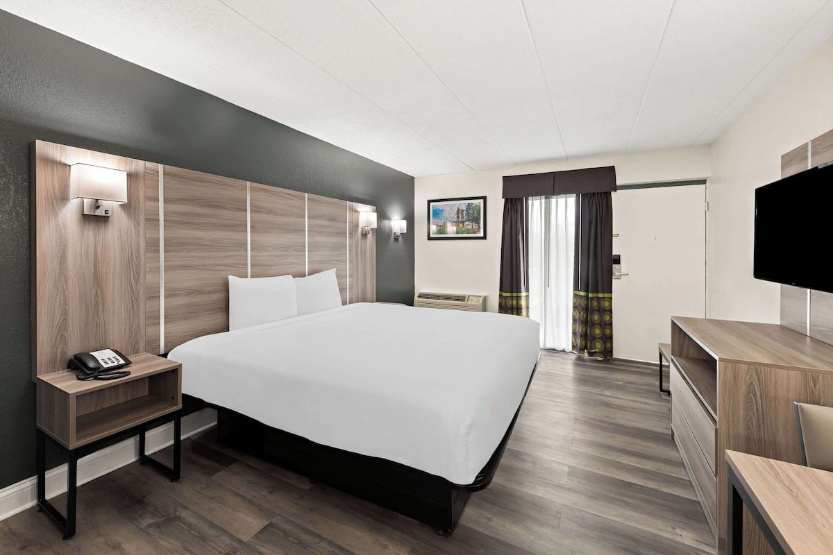 Une chambre d’hôtel avec un grand lit, des tables de chevet, un bureau et une télévision.