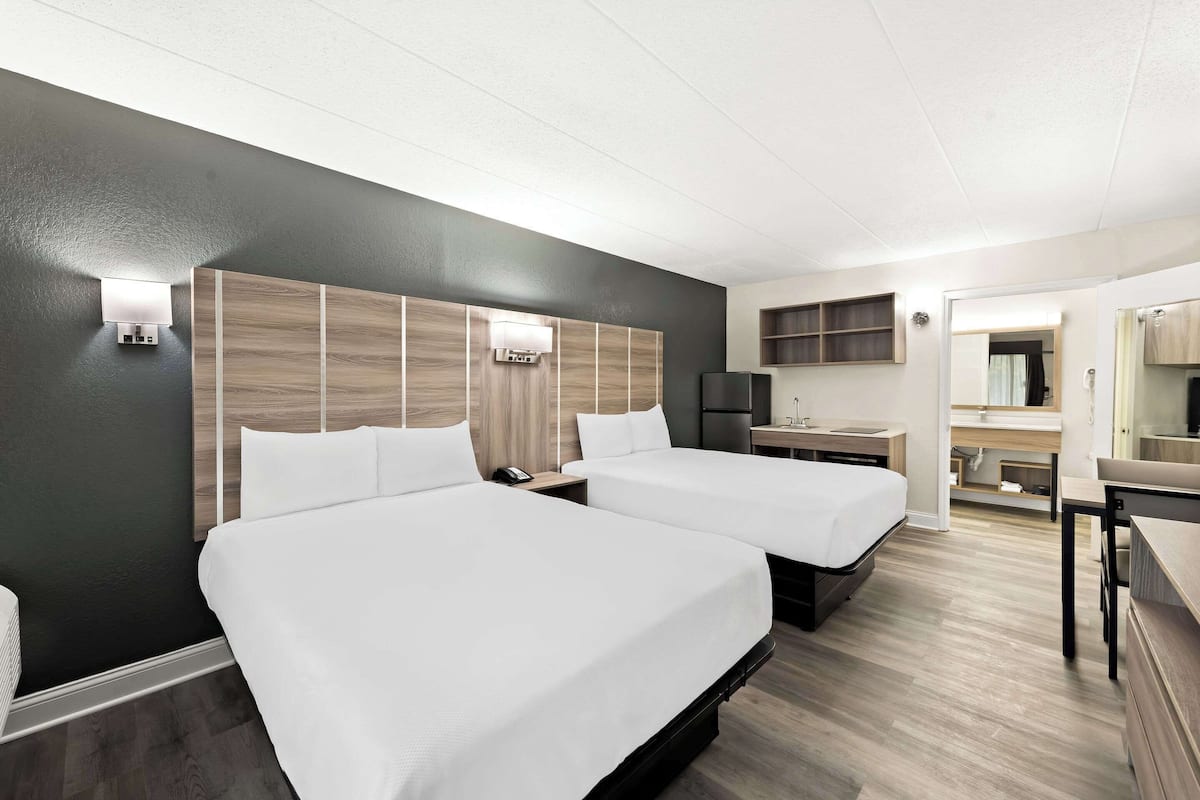 Une chambre d’hôtel avec deux lits, une petite kitchenette, une salle de bain et un bureau.