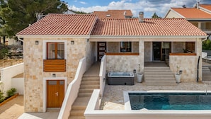 Et moderne hus med tegltag, swimmingpool og boblebad.