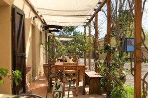 An outdoor patio with a wooden table and chairs, surrounded by potted plants and a pergola. - La Tonnaia - Apartment 1 ground floor (Lari)