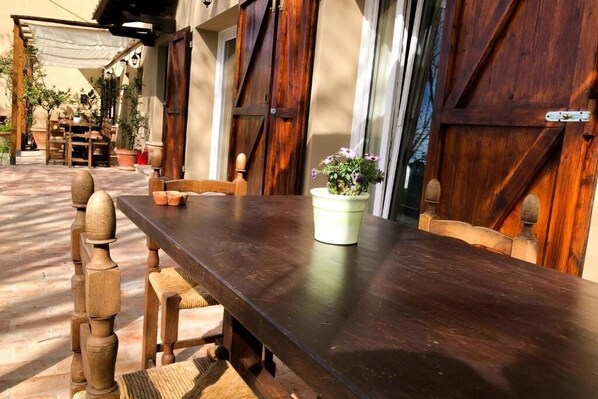 Een houten tafel met stoelen, een bloempot en een landelijke deur.