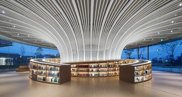 Et moderne bibliotek med buet reolindretning og et unikt loftdesign.