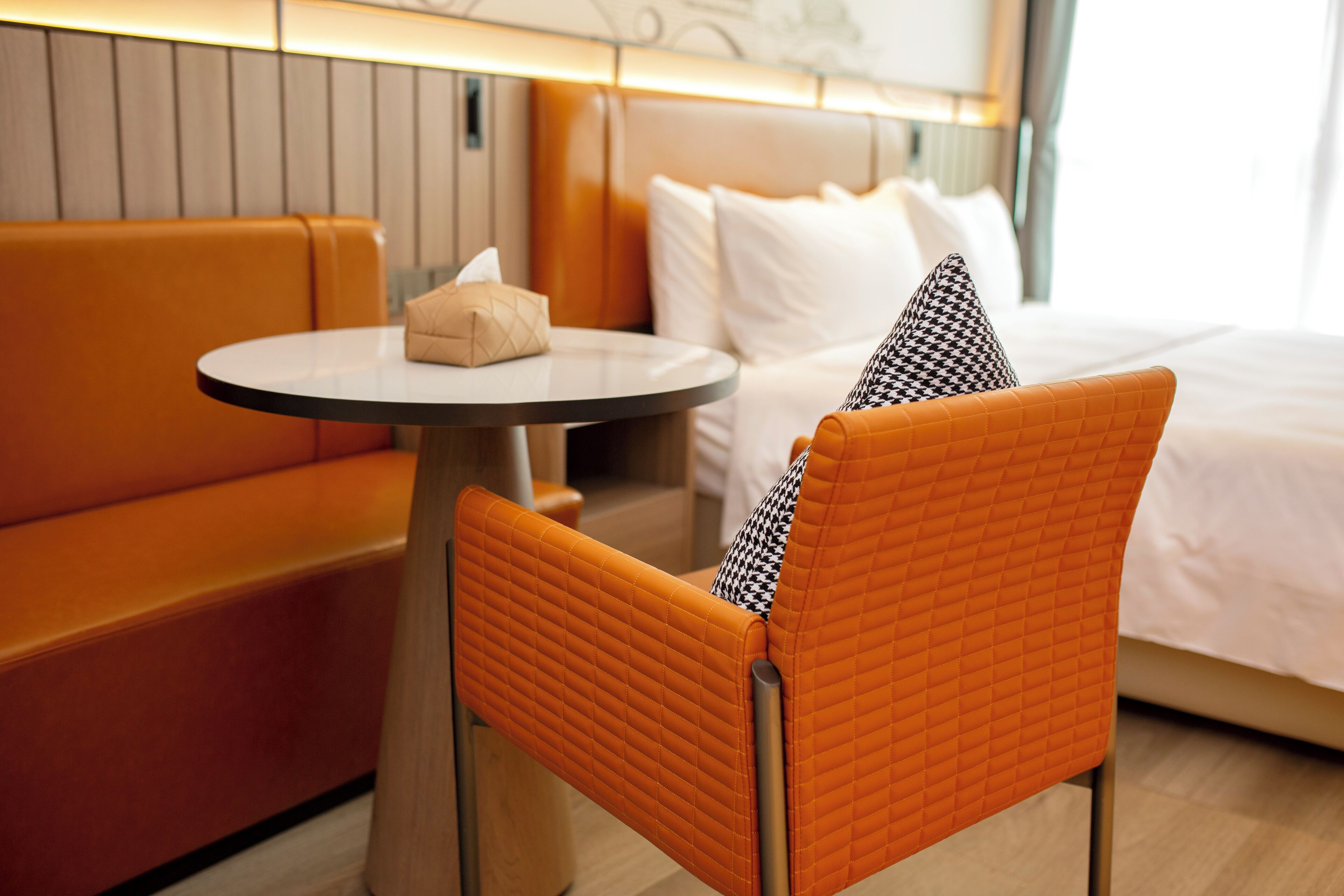 Ein Hotelzimmer mit einem Bett, einem runden Tisch und einem orangefarbenen Sessel.