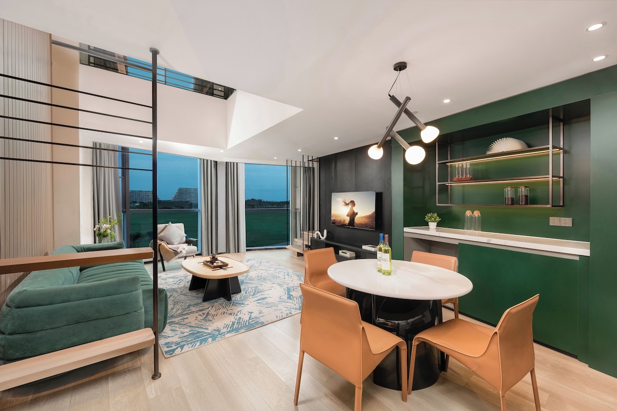A modern living room with a sofa, a dining table, chairs, and a TV.