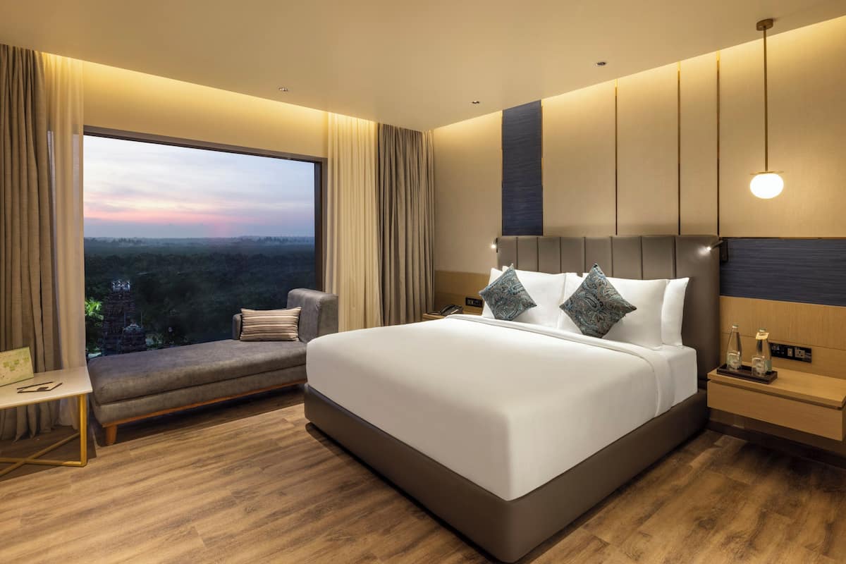 Een moderne hotelkamer met een groot bed, een zithoek en uitzicht op de stad.