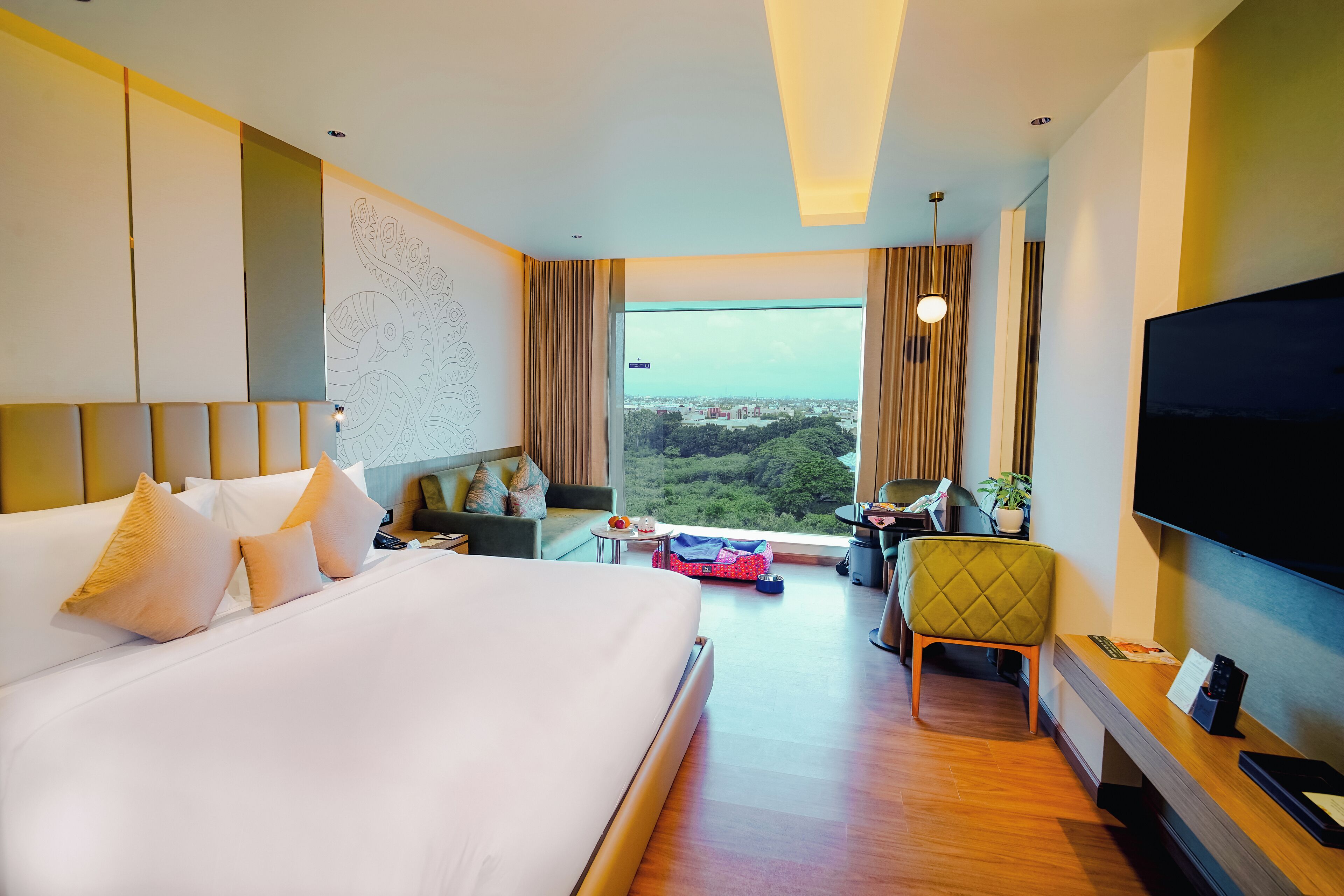 Habitación de hotel con una cama grande, un escritorio, una silla, un televisor y vistas a la ciudad.