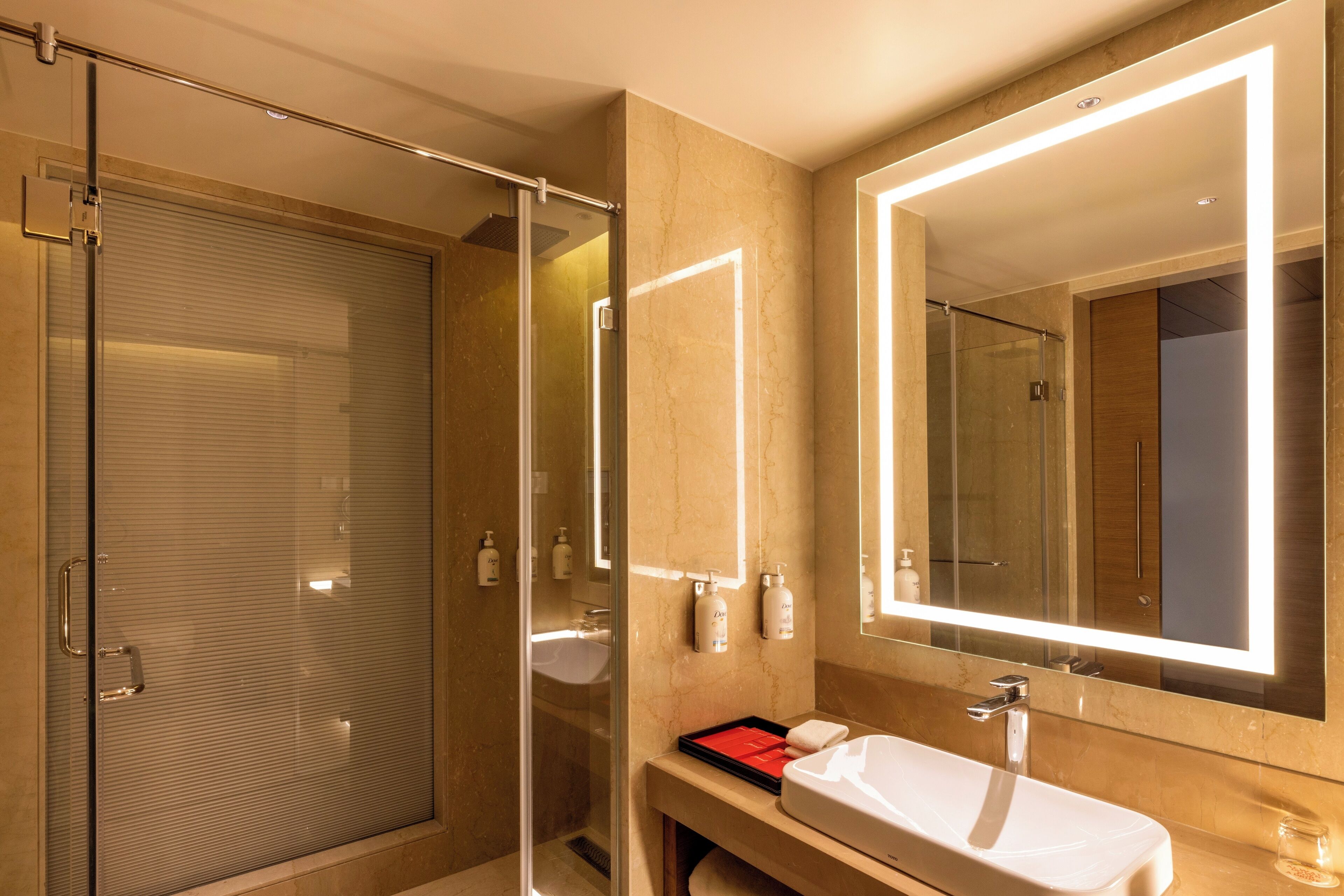 A modern bathroom with a glass shower enclosure, a large mirror, and a white sink.