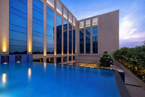 Un edificio moderno con un amplio área de piscina, ventanas grandes e iluminación exterior.