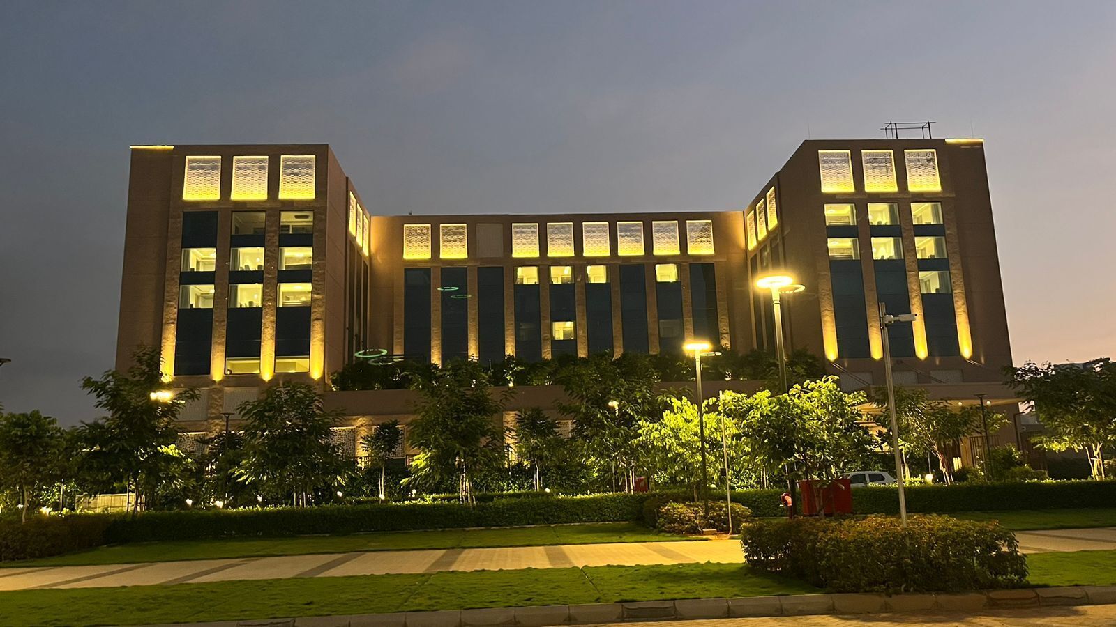 A modern building with a symmetrical facade, large windows, and a well-maintained surrounding garden.