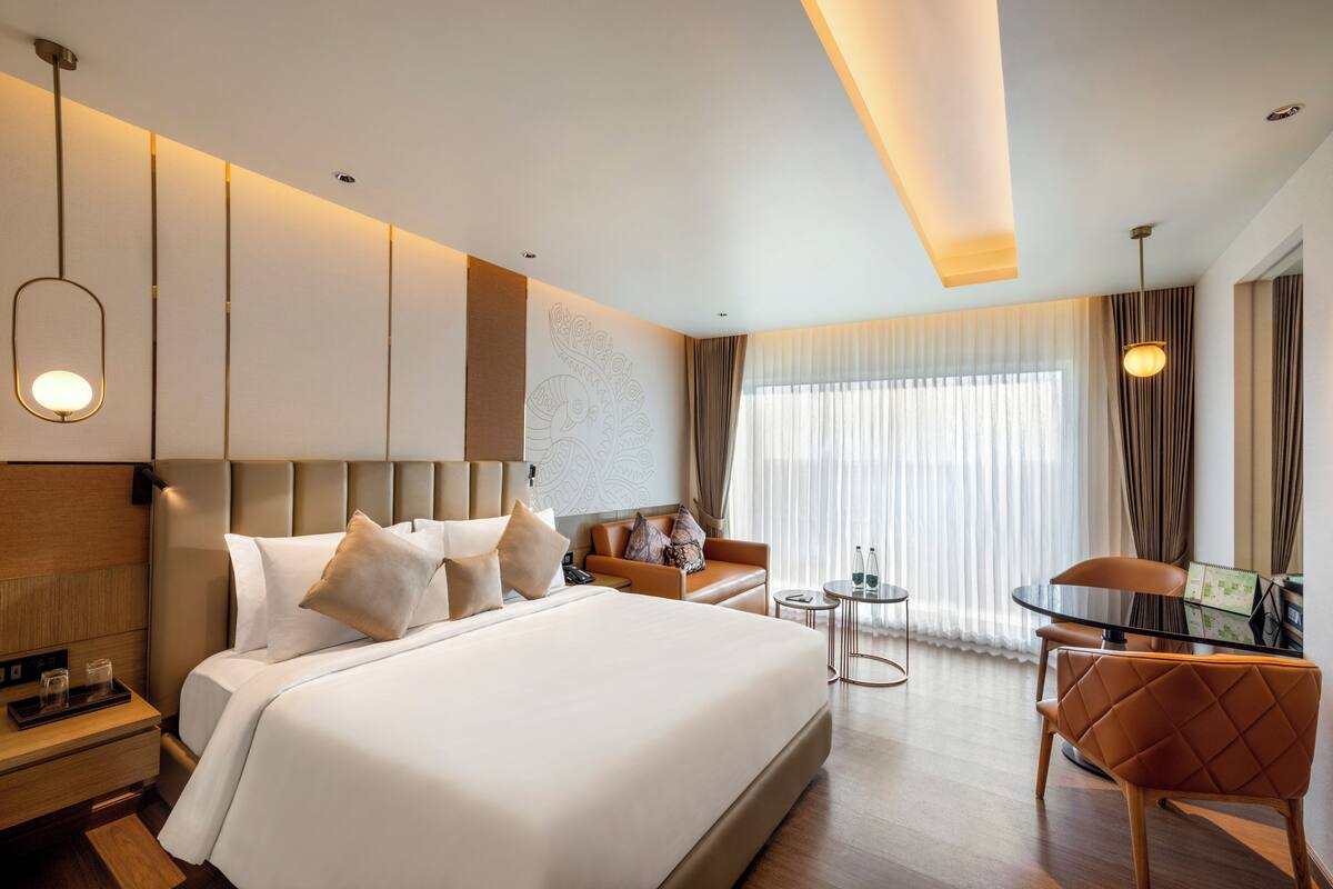 Een moderne hotelkamer met een groot bed, een bank, een tafeltje en een stoel.
