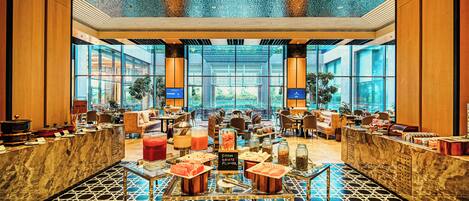 A spacious lobby with a high ceiling, large windows, and a marble reception desk.