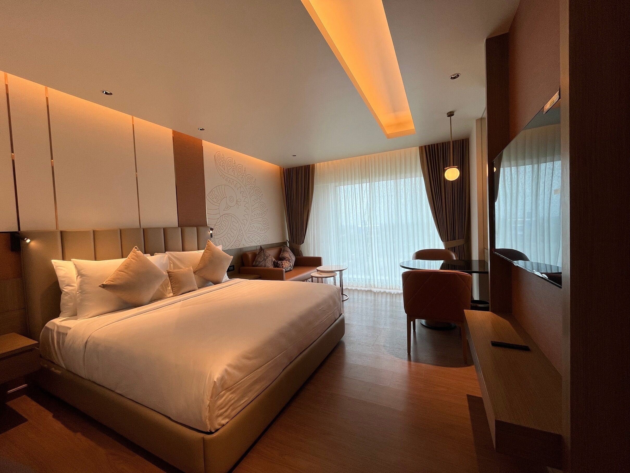 Una habitación de hotel moderna con una cama grande, un escritorio, una silla y un televisor.