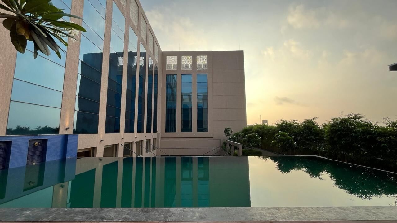 Un edificio moderno con una facciata in vetro riflettente e una piscina di fronte.