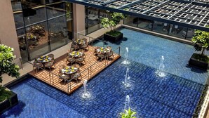 Un área de piscina en la azotea con asientos y vistas de la ciudad.