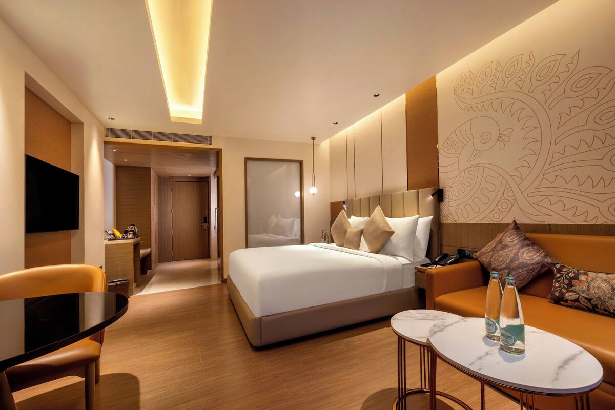 Een moderne hotelkamer met een groot bed, een bank, een klein tafeltje en een televisie.