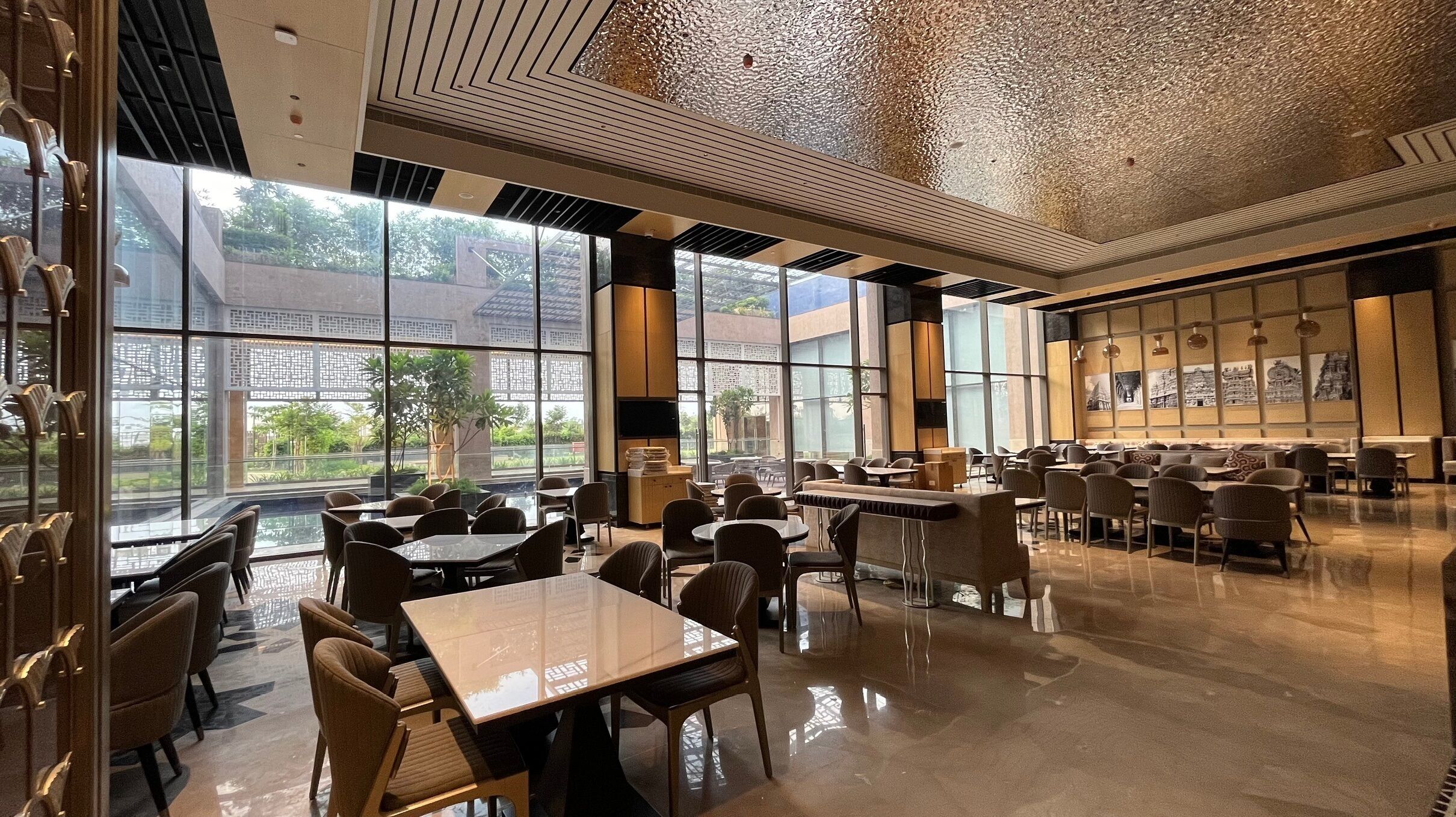 A spacious restaurant with high ceilings, large windows, and a variety of seating arrangements.