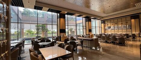 A spacious restaurant with high ceilings, large windows, and a variety of seating arrangements.