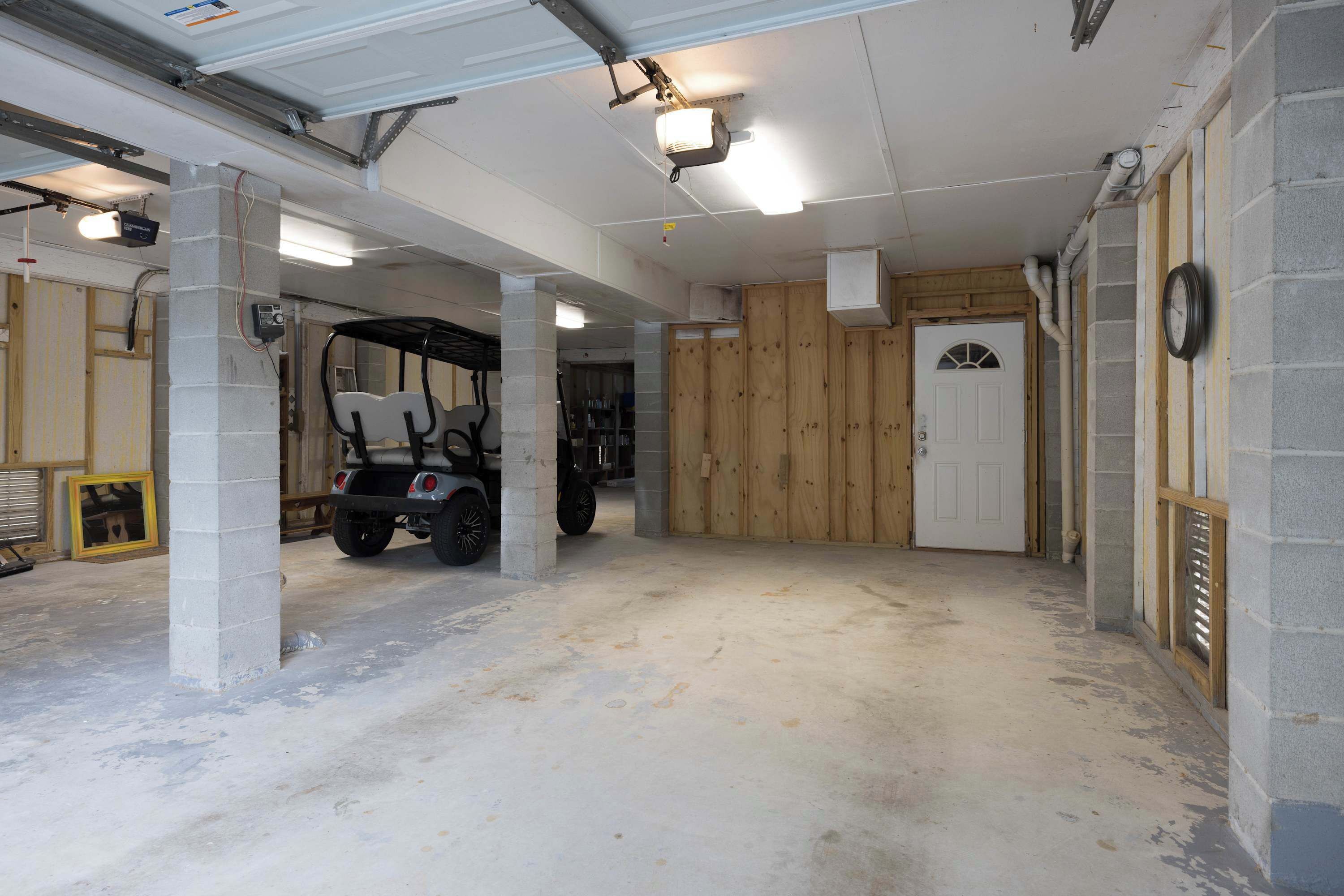 Un garage avec un sol en béton, un véhicule de golf et une porte en bois.