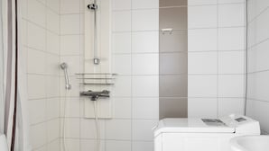A compact bathroom with a shower, toilet, and washing machine. - Kotimaailma Aparthotel Kamppi 1BR with balcony (Helsinki)