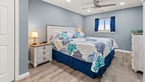A bedroom with a bed, nightstand, dresser, and a ceiling fan.