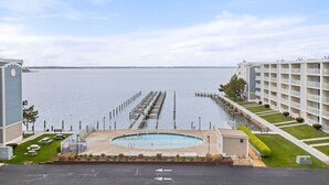 A hotel with a pool, a pier extending into the water, and a view of the sea.