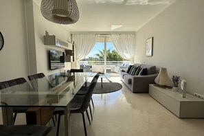 Relax in this stylish living space with a glass dining table and comfortable sofa, offering a view of the outdoors.