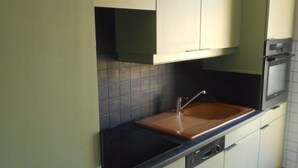 A kitchen with green cabinets, a black countertop, and a built-in oven.