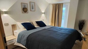 A bedroom with a bed, bedside tables, a nightstand, a window with curtains, and wall-mounted lighting. - 10 minutes from the sea, a newly renovated appartment for 6 person
 (labin)