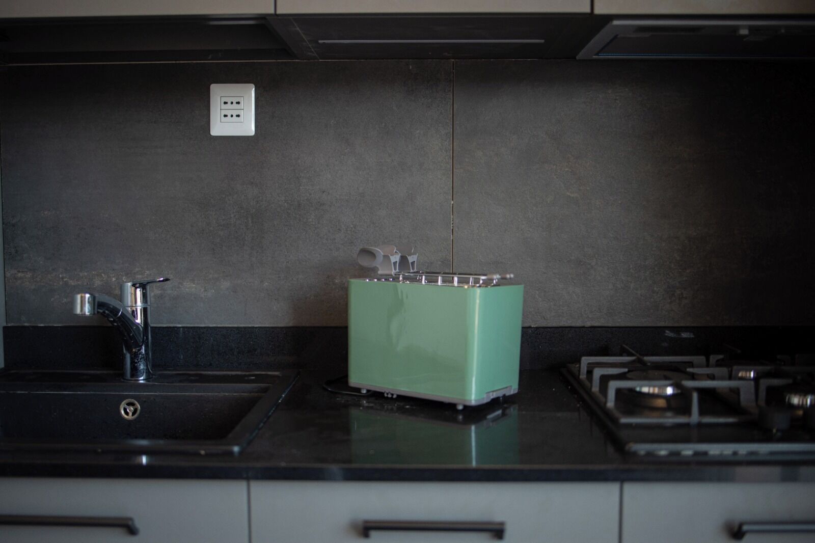 Eine Küche mit Spüle, einem grünen Toaster und einem Herd.