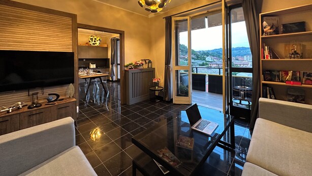 Un saló modern amb una taula de café de vidre, un sofà, una televisió i una zona de menjador amb taula i cadires.
