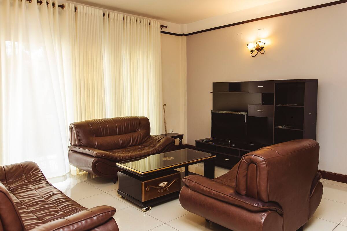 Ein Wohnzimmer mit Ledersofas, einem Glastisch und einer schwarzen Unterhaltungsanlage.