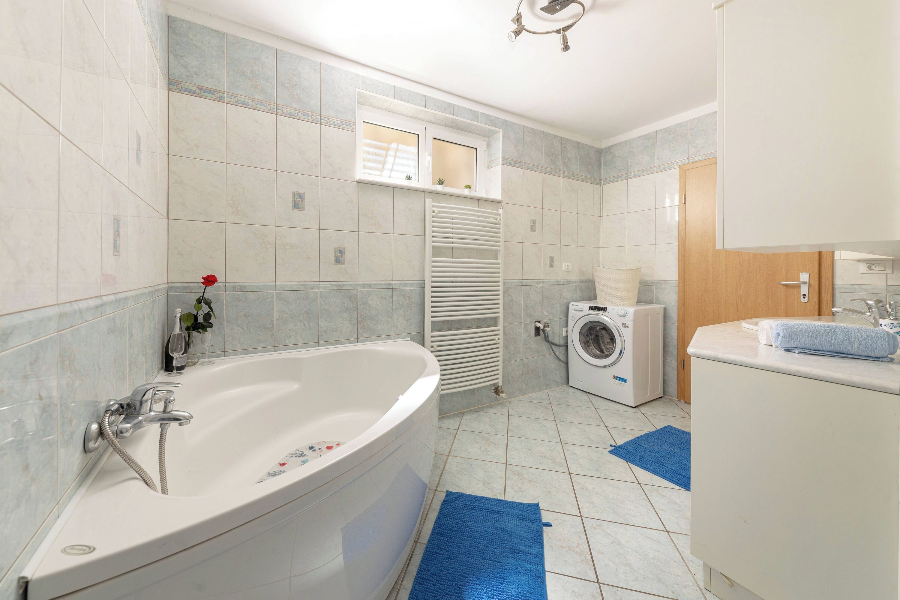 Un baño moderno con una bañera independiente, un ventanal integrado, una lavadora y un lavabo con toalla.