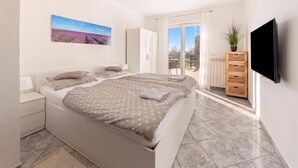 A bedroom with two beds, a TV, a wardrobe, and a balcony with a view. - Serene Retreat St. Anton (Koper)
