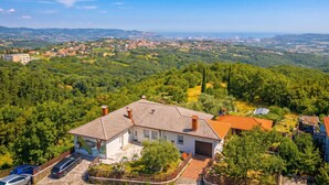 A house with a tiled roof, surrounded by lush greenery and a distant view of a town. - Serene Retreat St. Anton (Koper)