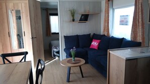 A modern living room with a sofa, a small round table, and a dining area.