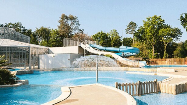 A water park with a large pool, a water slide, and a greenhouse structure.